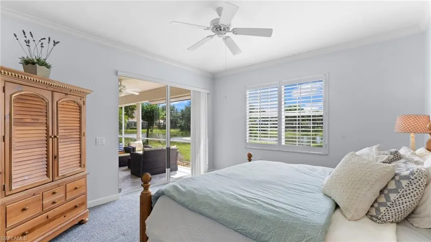 Carpeted bedroom with ceiling fan, access to exterior, and crown molding