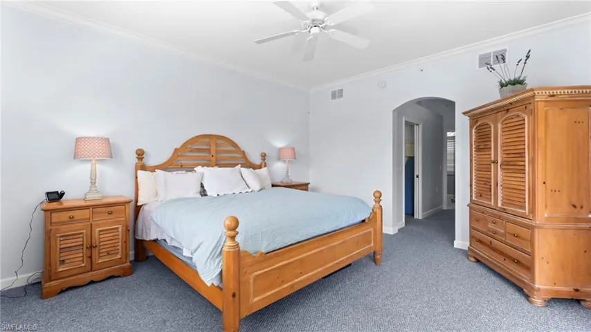 Carpeted bedroom with ornamental molding and ceiling fan