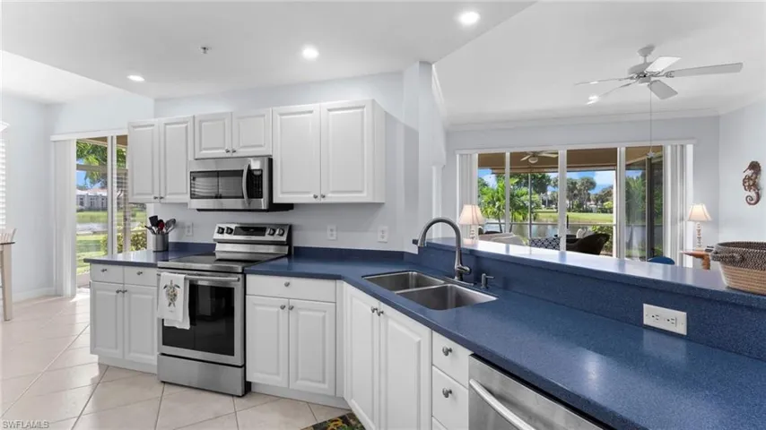 Kitchen with sink, white cabinets, stainless steel appliances, crown molding, and ceiling fan