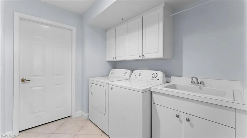Washroom with washer and clothes dryer, cabinets, sink, and light tile patterned flooring