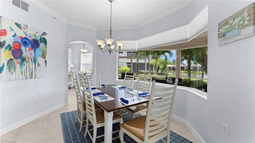 Tiled dining space with crown molding, an inviting chandelier, and a wealth of natural light