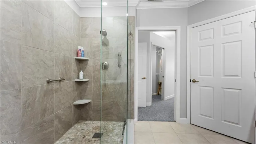 Bathroom featuring ornamental molding, walk in shower, and tile patterned floors