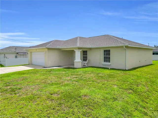 Rear view of house with concrete driveway, a garage, and stucco siding