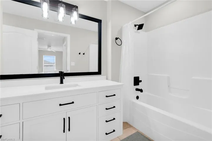 Bathroom featuring shower / tub combo with curtain, vanity, tile patterned flooring, and a ceiling fan