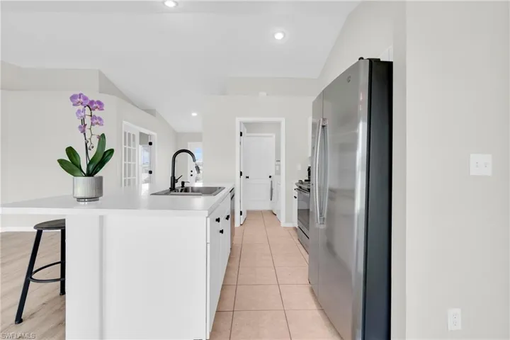 Kitchen with stainless steel appliances, light countertops, a center island with sink, a breakfast bar, and white cabinetry