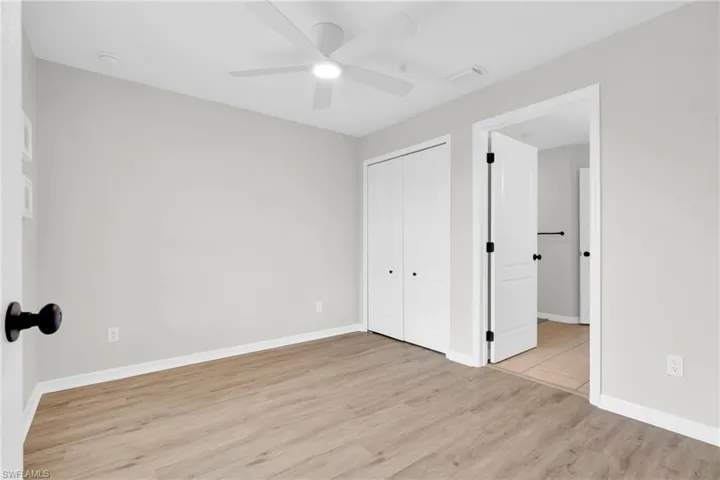 Unfurnished bedroom with light wood-style flooring, a closet, and a ceiling fan