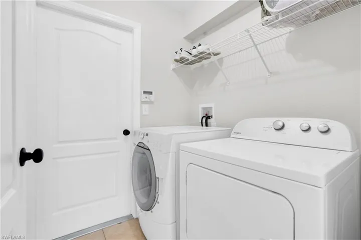 Washroom with separate washer and dryer and light tile patterned floors