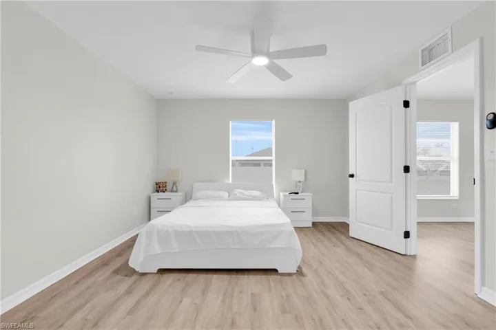 Bedroom with light wood-style floors, multiple windows, and a ceiling fan