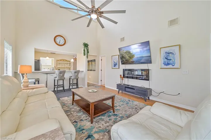 Living room featuring hardwood / wood-style floors, ceiling fan, and a towering ceiling