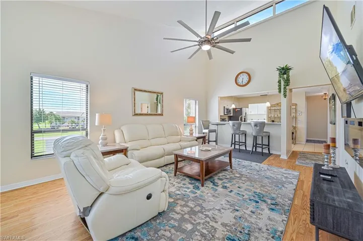 Living room featuring a healthy amount of sunlight, a high ceiling, light wood-type flooring, and ceiling fan