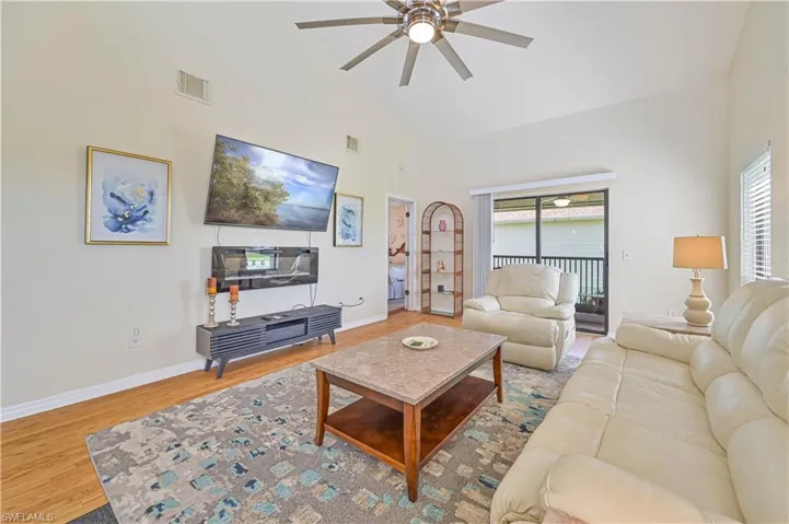 Living room featuring light hardwood / wood-style flooring, a wealth of natural light, ceiling fan, and high vaulted ceiling