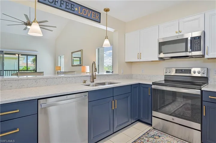 Kitchen with ceiling fan, sink, dishwasher, lofted ceiling, and light tile patterned floors