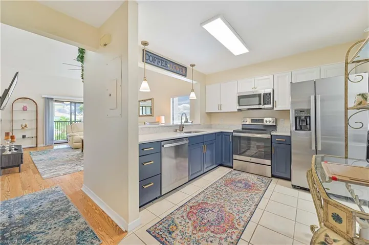 Kitchen featuring white cabinetry, blue cabinets, sink, light hardwood / wood-style floors, and appliances with stainless steel finishes