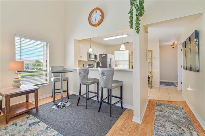 Kitchen featuring a kitchen bar, white cabinetry, stainless steel appliances, and light hardwood / wood-style floors