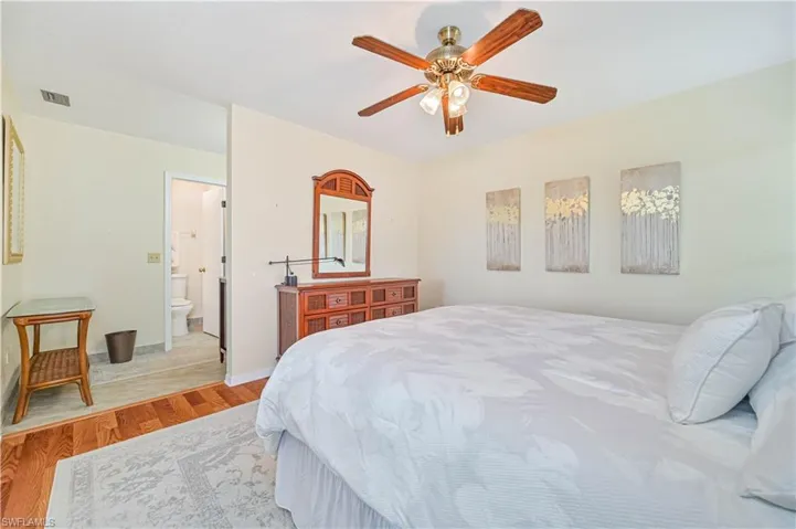 Bedroom with light hardwood / wood-style flooring, ensuite bath, and ceiling fan
