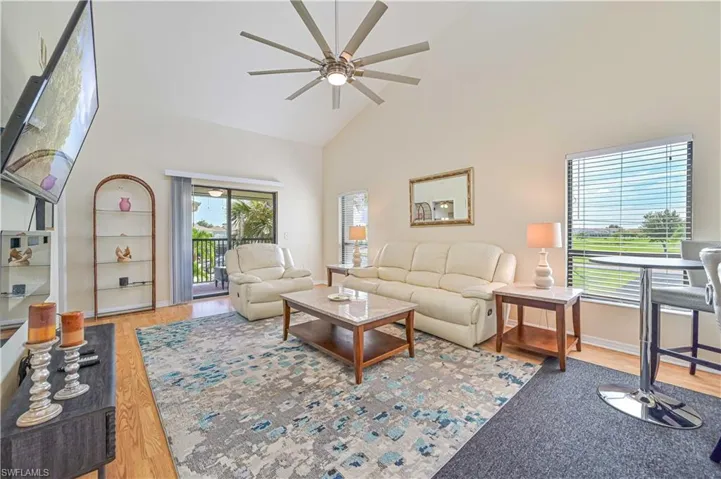 Living room featuring ceiling fan, a high ceiling, and light hardwood / wood-style flooring