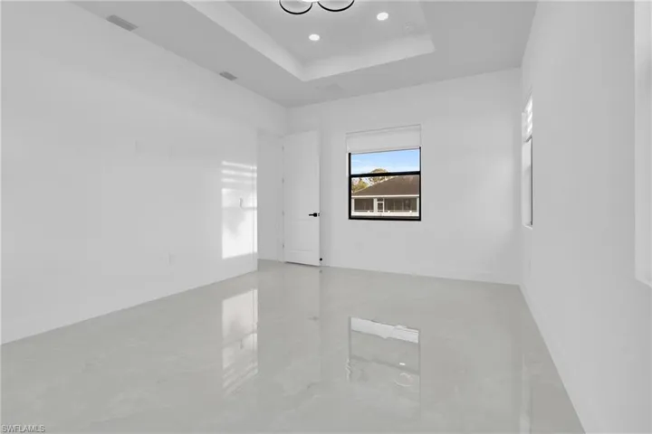 Empty room featuring a tray ceiling and recessed lighting