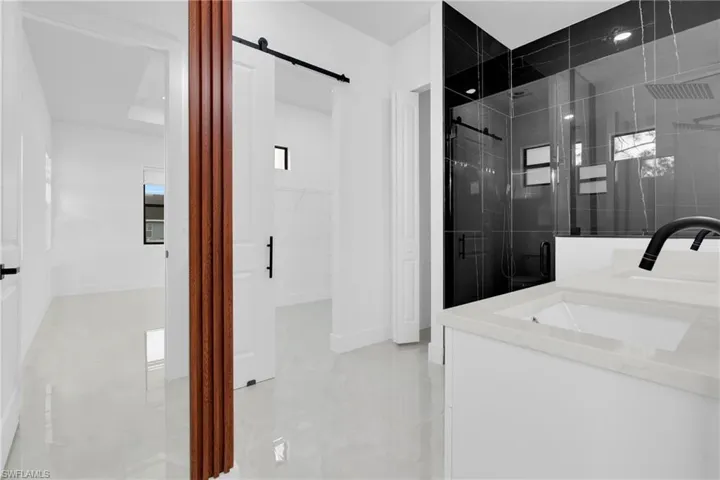 Bathroom featuring double vanity, a shower stall, and a walk in closet