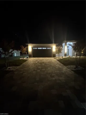 View of front of home at night with decorative driveway