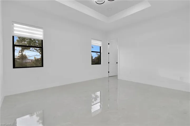 Spare room with a tray ceiling and finished concrete floors