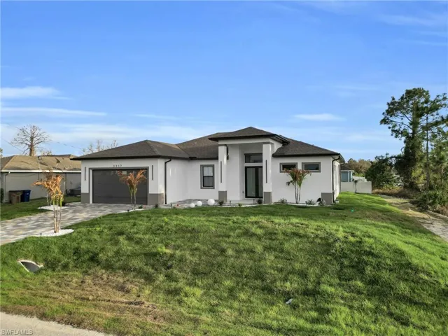 Prairie-style home featuring stucco siding, concrete driveway, a front yard, a garage, and a shingled roof