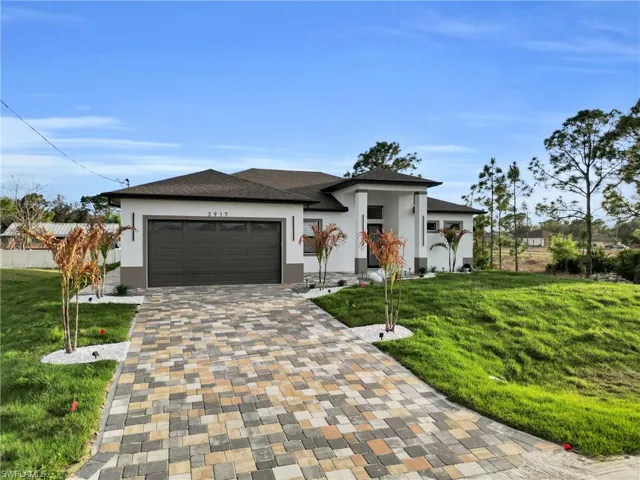 Prairie-style house with a front lawn, stucco siding, and driveway
