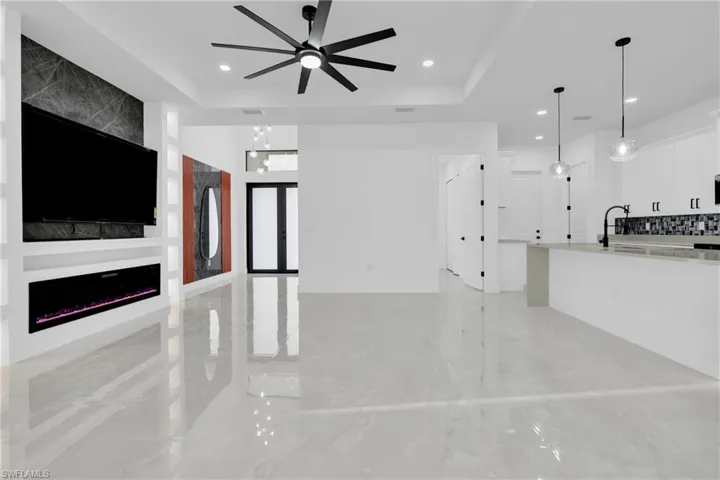 Unfurnished living room featuring a raised ceiling, a fireplace, ceiling fan, and a chandelier