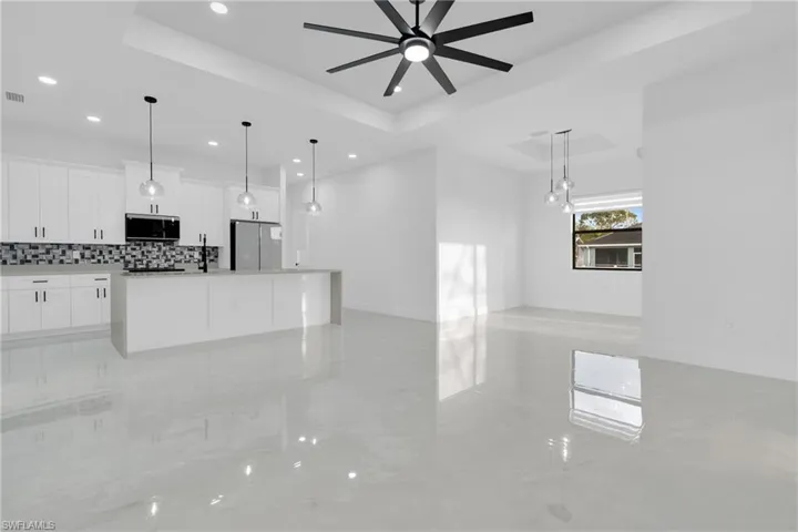 Unfurnished living room featuring a raised ceiling and ceiling fan, Dining area.