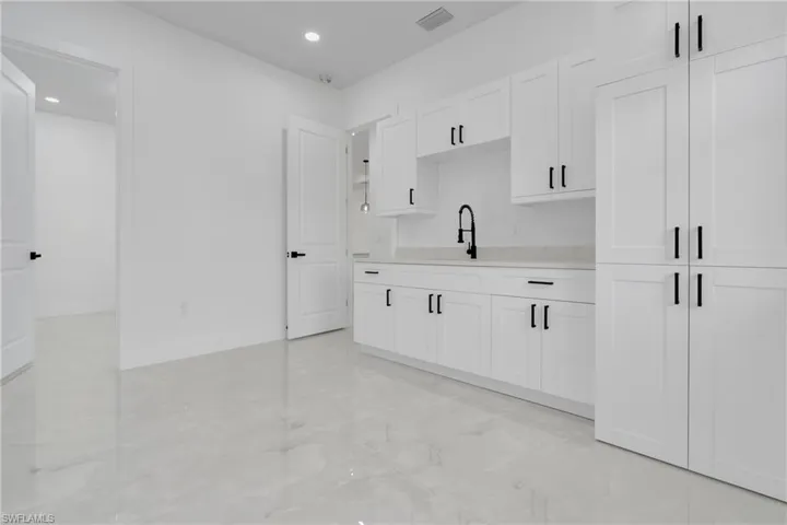 Mother-in-Law Suite,  Kitchenette with white cabinets, recessed lighting, and light stone countertops. "Washer/Dryer combo unit included" with dedicated hookups.