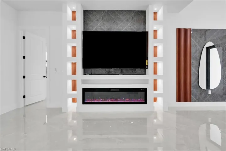 Unfurnished living room featuring a glass covered fireplace and built in shelves and Plus zize TV.