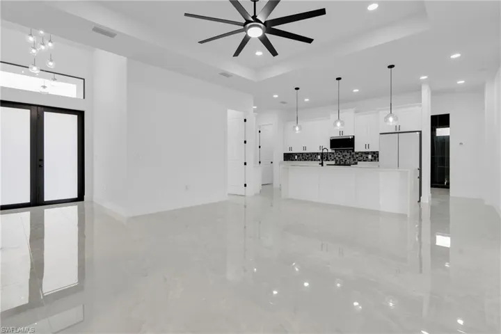 Unfurnished living room with french doors, a tray ceiling, and a ceiling fan