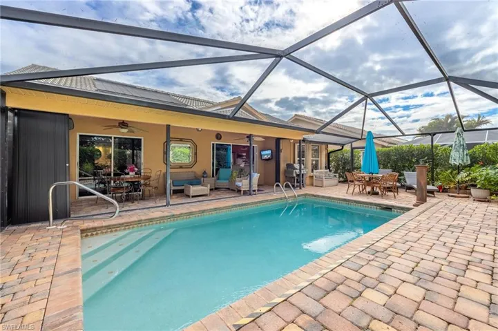 View of pool featuring glass enclosure, ceiling fan, a patio area, and outdoor lounge area