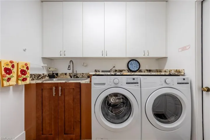 Laundry room featuring cabinets, sink, and washing machine and dryer