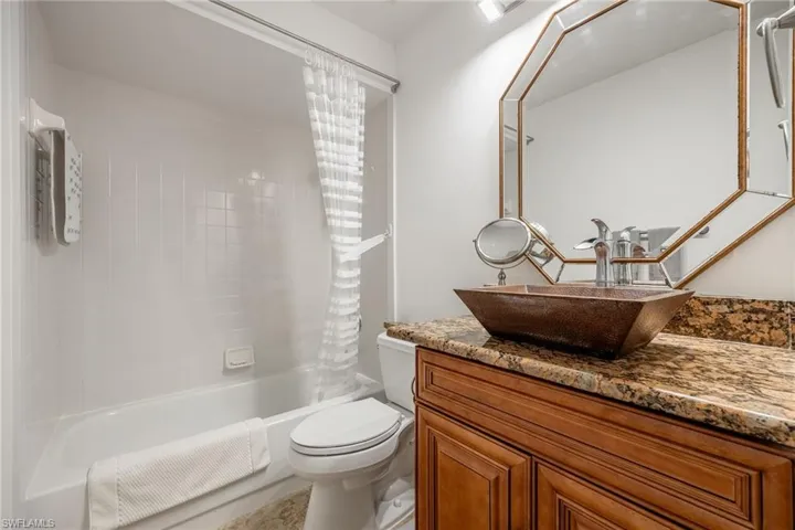 Full guest bathroom with toilet, vanity, and shower / tub combo with curtain