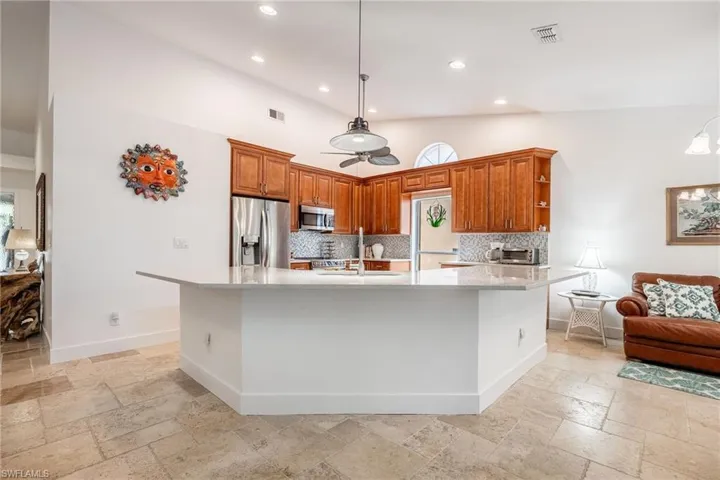 Kitchen featuring a large island, backsplash, hanging light fixtures, and stainless steel appliances