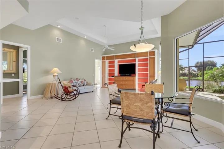 Dining room with a tray ceiling, light tile patterned floors, recessed lighting, a high ceiling, and a ceiling fan