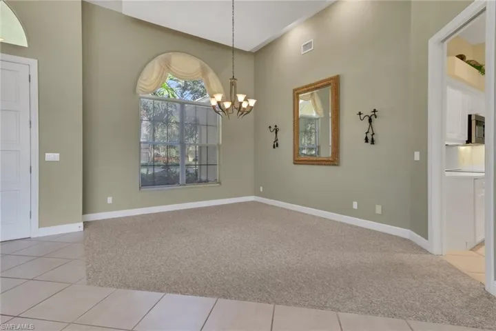 Unfurnished dining area with light carpet, light tile patterned floors, and a chandelier