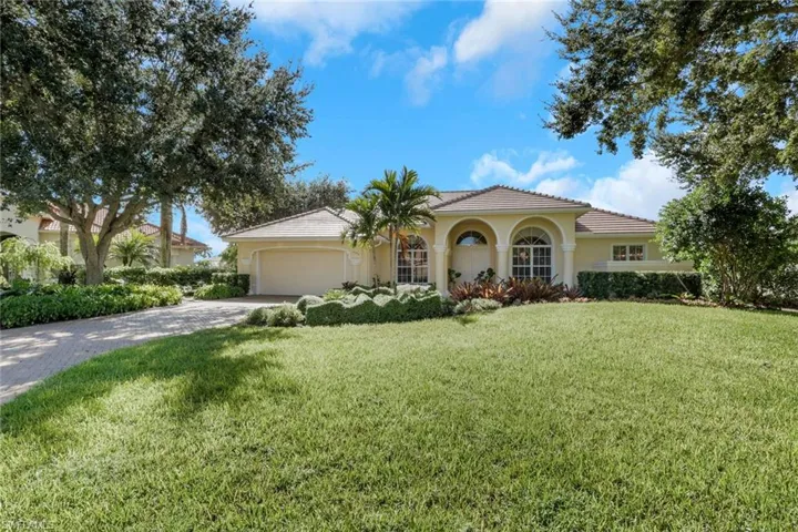 Mediterranean / spanish home featuring a front yard, a tiled roof, stucco siding, driveway, and a garage