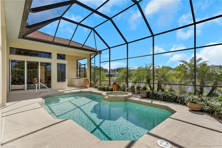 View of swimming pool with a sunroom, glass enclosure, a patio, and a pool with connected hot tub