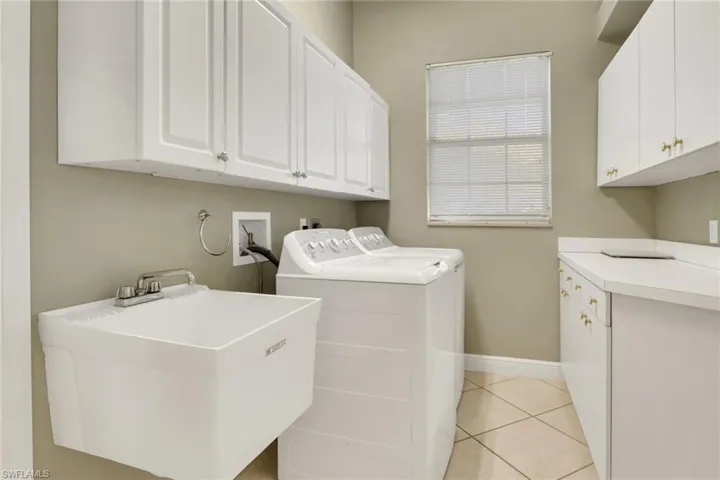 Laundry area with light tile patterned floors, cabinet space, and washer and dryer