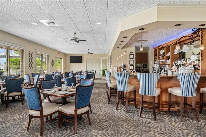 Dining space featuring dark carpet, ceiling fan, and a drop ceiling