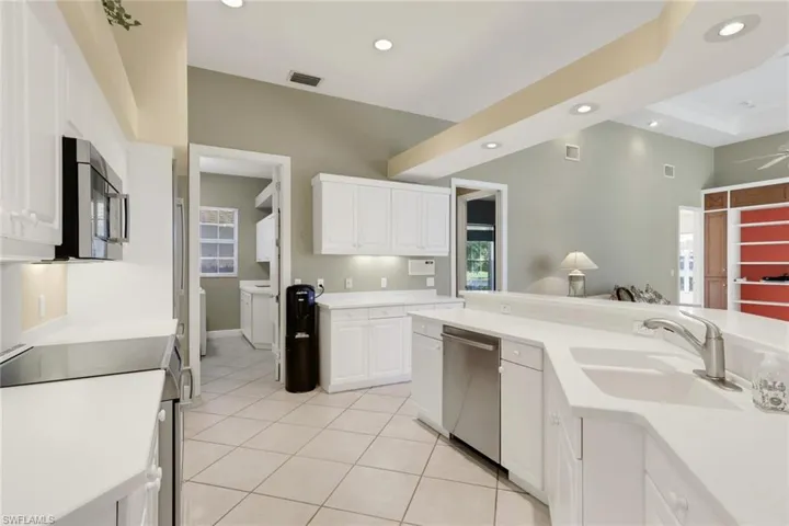 Kitchen with stainless steel appliances, white cabinets, recessed lighting, and light tile patterned flooring