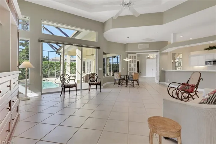 Living room with a sunroom, a high ceiling, light tile patterned flooring, and a ceiling fan