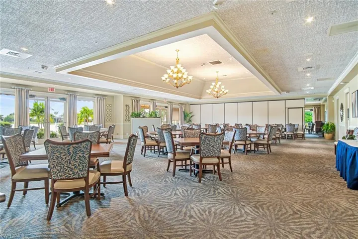 Carpeted dining area with a raised ceiling, healthy amount of natural light, ornamental molding, and a chandelier
