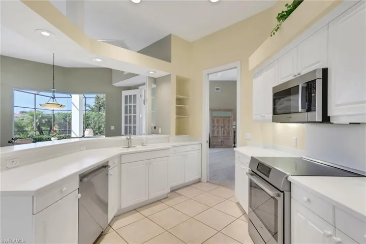 Kitchen with appliances with stainless steel finishes, white cabinets, decorative light fixtures, light tile patterned floors, and recessed lighting