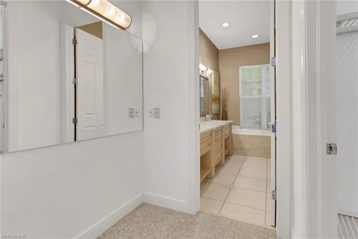 Bathroom with light tile patterned flooring, vanity, recessed lighting, light carpet, and a bathtub