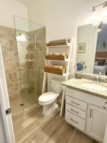 Ensuite bathroom with vanity, a walk in shower, and wood tiled floors
