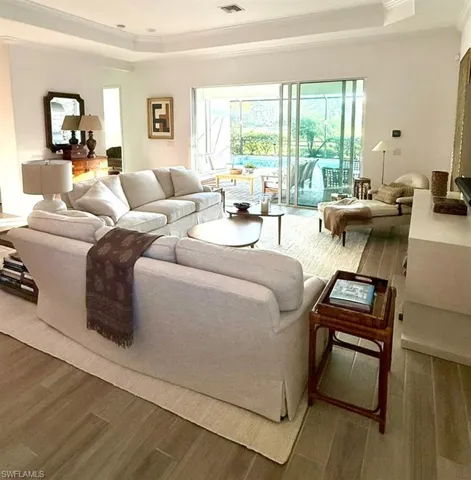 Living area featuring a raised ceiling, wood finished floors, and ornamental molding