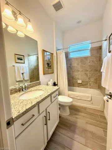 Full bath with dark wood-style floors, vanity, and shower / bath combo