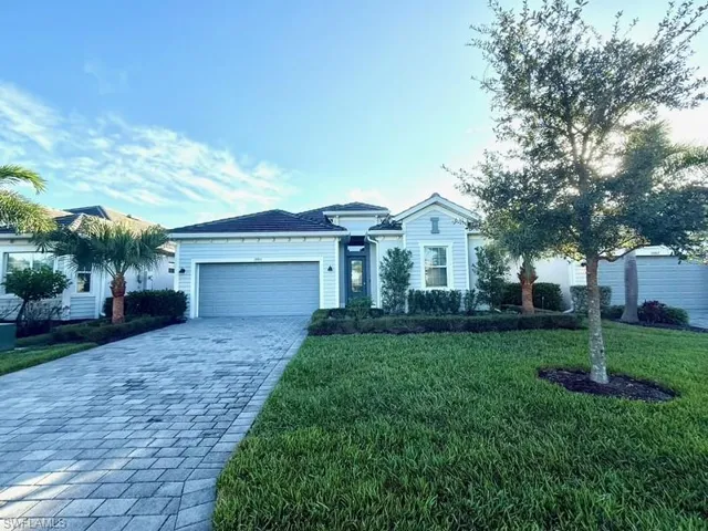Ranch-style house featuring a front lawn, decorative driveway, and an attached garage